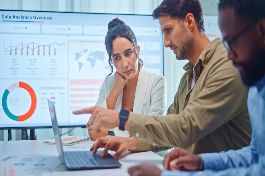 Marketing team analysing data on a laptop with charts on screen, discussing strategies for How to Choose the Best Digital Marketing Agency in Karachi.